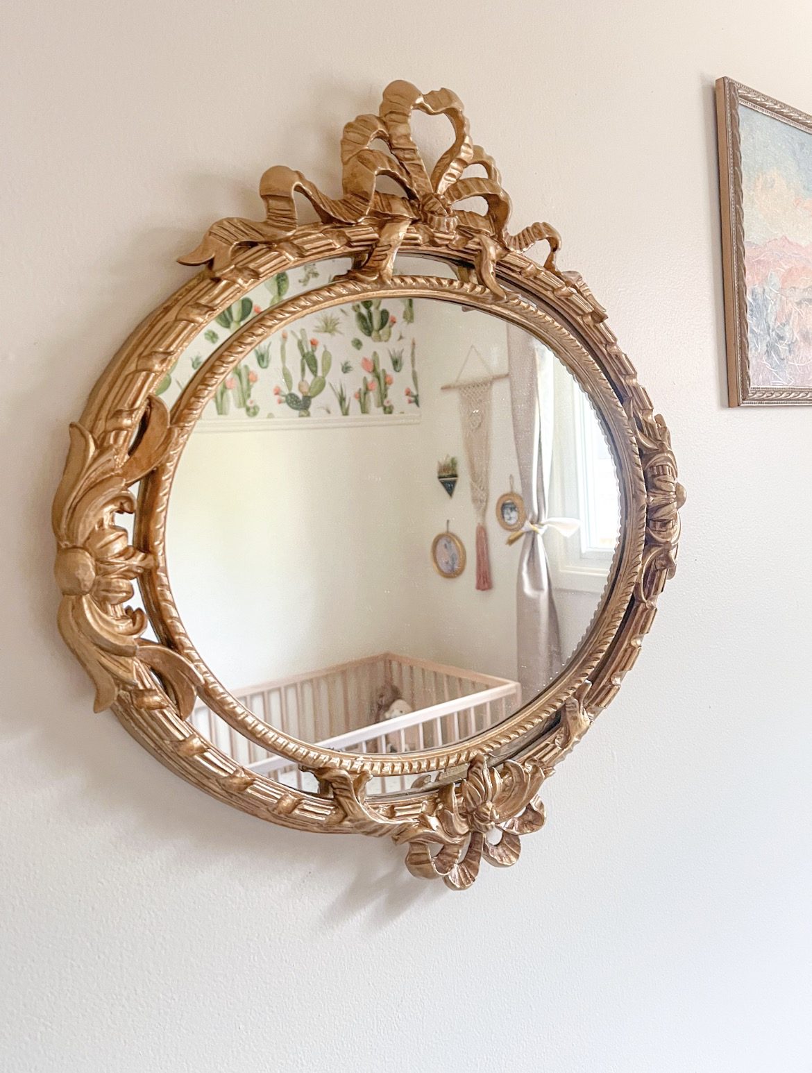 A gilded bow mirror reflecting a cactus nursery